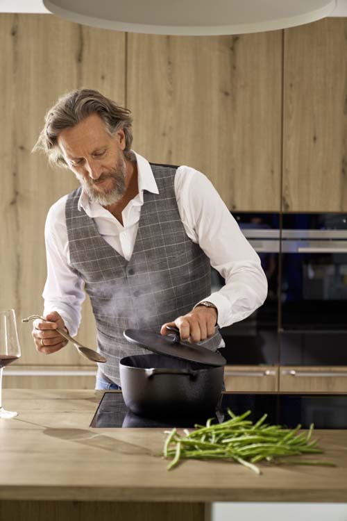 Maatwerkkeuken in houtlook Man aan het koken in maatwerk keuken