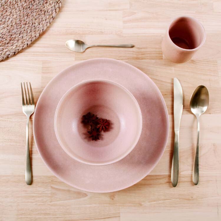 Tafel gedekt met roze servies en gouden bestek